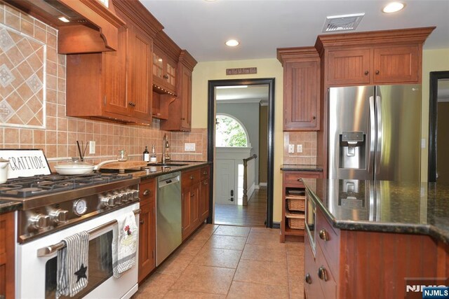 126 Darrow Dr, North Haledon, NJ 07508 - kitchen featuring appliances with stainless steel finishes, a sink, decorative backsplash, brown cabinets, and dark stone countertops