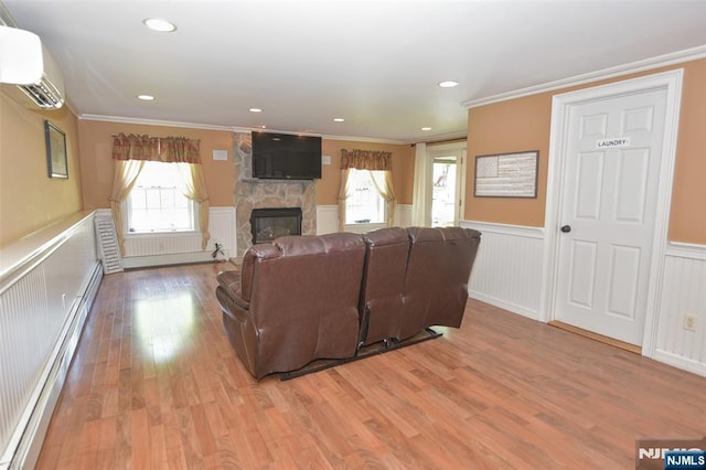 126 Darrow Dr, North Haledon, NJ 07508 - living room with a wainscoted wall, a stone fireplace, a wall unit AC, light wood-style flooring, and crown molding