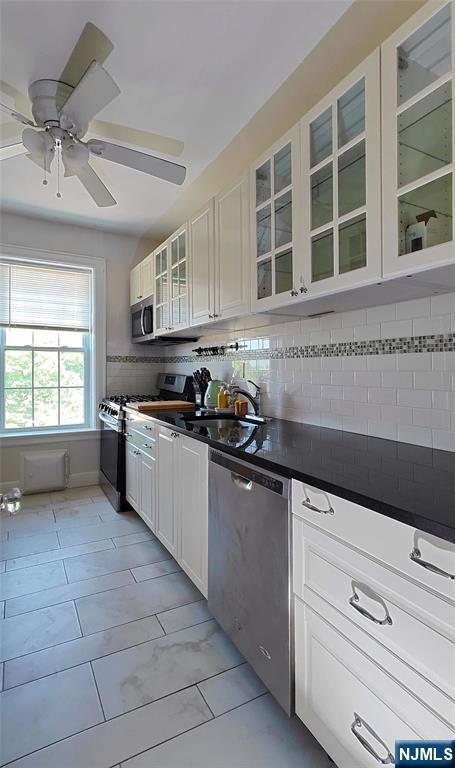 275 Engle St Unit G4, Englewood, NJ 07631 - kitchen with stainless steel appliances, dark countertops, a sink, glass insert cabinets, and white cabinets