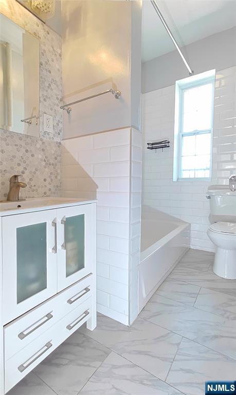 275 Engle St Unit G4, Englewood, NJ 07631 - bathroom with toilet, marble finish flooring, washtub / shower combination, vanity, and decorative backsplash