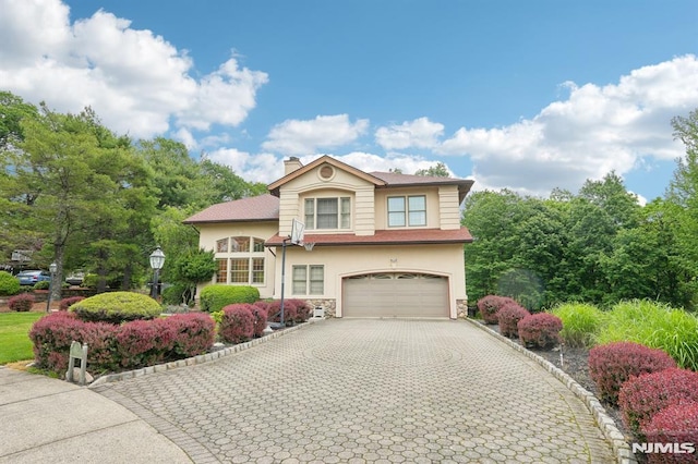 45 Dykers Farm Rd, North Haledon, NJ 07508 - view of front of home featuring an attached garage, decorative driveway, stucco siding, a chimney, and stone siding
