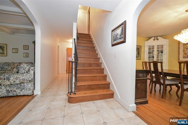 76 Spring Valley Rd, Montvale, NJ 07645 - stairway featuring arched walkways, baseboards, wood finished floors, and a chandelier
