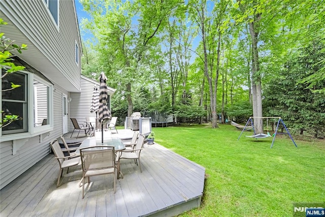 66 Hoffman Ct, River Vale, NJ 07675 - wooden terrace with a trampoline, outdoor dining area, a lawn, and view of scattered trees