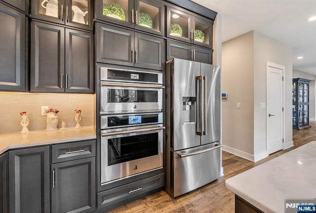 15 Meadowbrook Rd, Upper Saddle River, NJ 07458 - kitchen with stainless steel appliances, baseboards, decorative backsplash, light wood finished floors, and light countertops