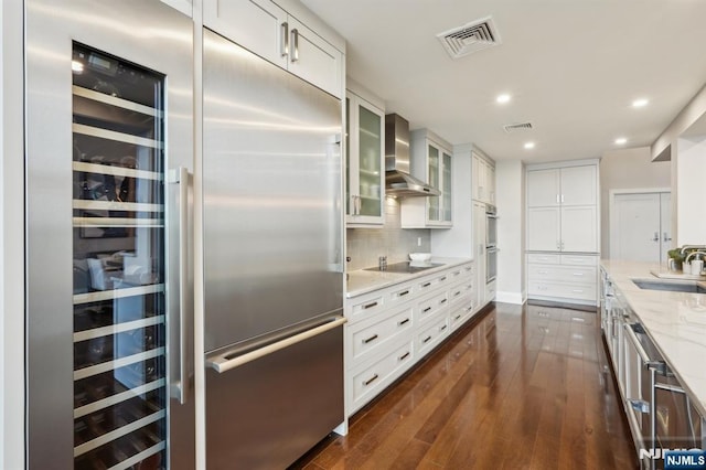 1360 Hamburg Tpke Unit 702, Wayne, NJ 07470 - kitchen with wall chimney range hood, stainless steel appliances, a sink, light stone countertops, and white cabinets