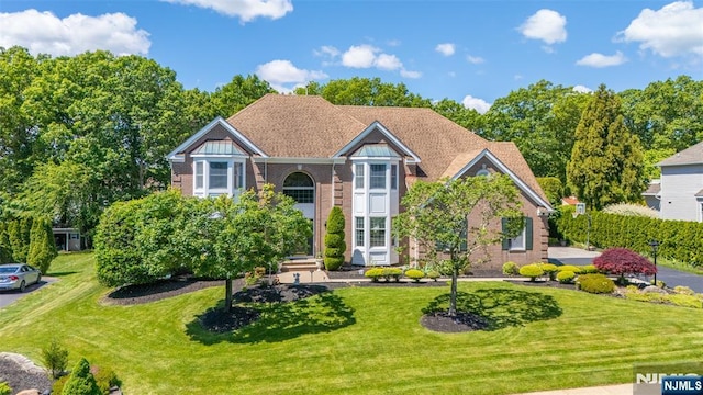 - traditional-style home with a front lawn and brick siding