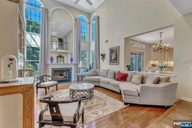  - living room with a ceiling fan, a towering ceiling, plenty of natural light, hardwood / wood-style floors, and a high end fireplace