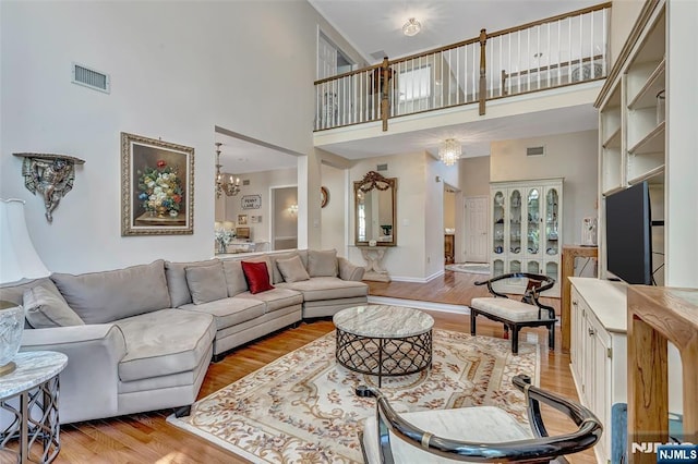  - living room featuring a towering ceiling, light wood finished floors, and a chandelier