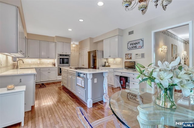  - kitchen featuring stainless steel appliances, a sink, light countertops, decorative backsplash, and recessed lighting