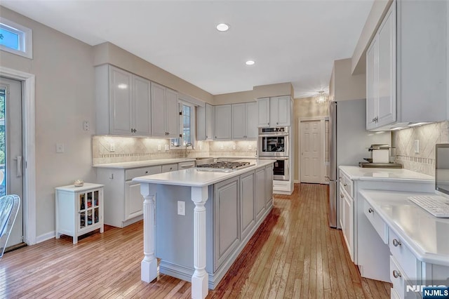  - kitchen with appliances with stainless steel finishes, light countertops, light wood-style flooring, decorative backsplash, and recessed lighting