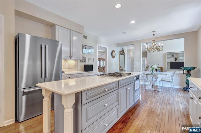  - kitchen featuring stainless steel appliances, light wood finished floors, light countertops, a chandelier, and recessed lighting