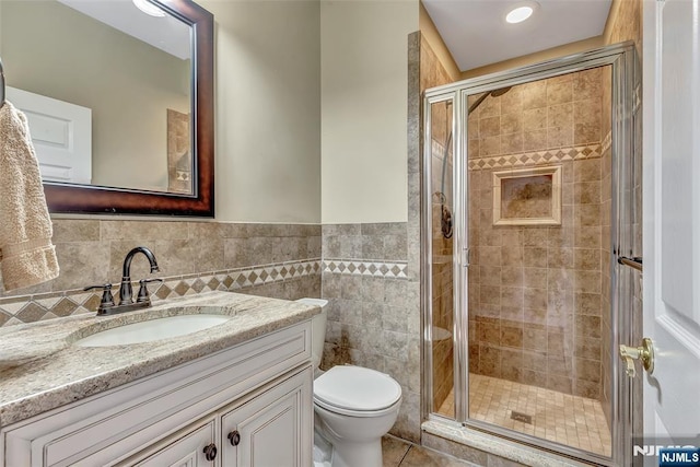 - bathroom with vanity, toilet, a shower stall, tile patterned flooring, and a wainscoted wall