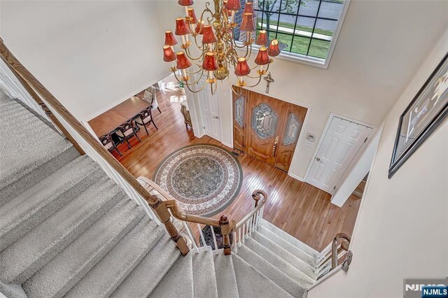  - entrance foyer with a chandelier, stairway, wood finished floors, and baseboards