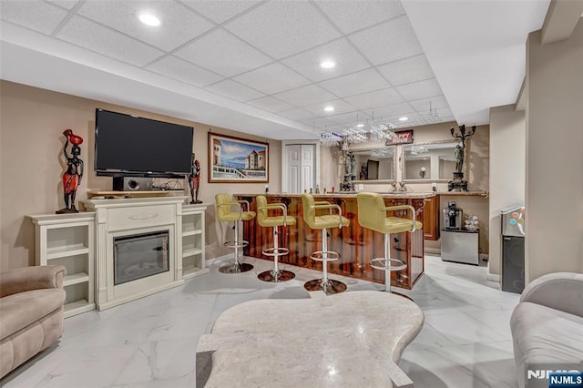 - indoor wet bar featuring light marble finish flooring, recessed lighting, a paneled ceiling, and baseboards