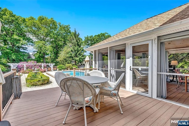  - wooden deck with an outdoor pool, outdoor dining space, and a sunroom