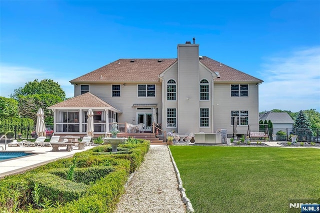  - back of property with a sunroom, a patio, a chimney, roof with shingles, and a deck