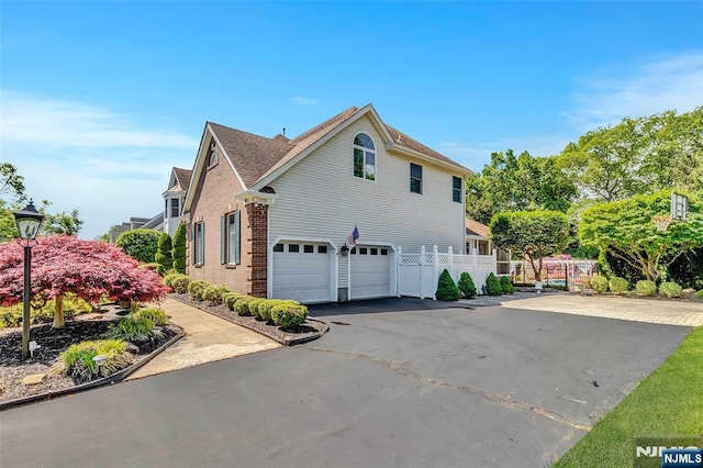  - view of home's exterior with asphalt driveway, an attached garage, brick siding, and a shingled roof