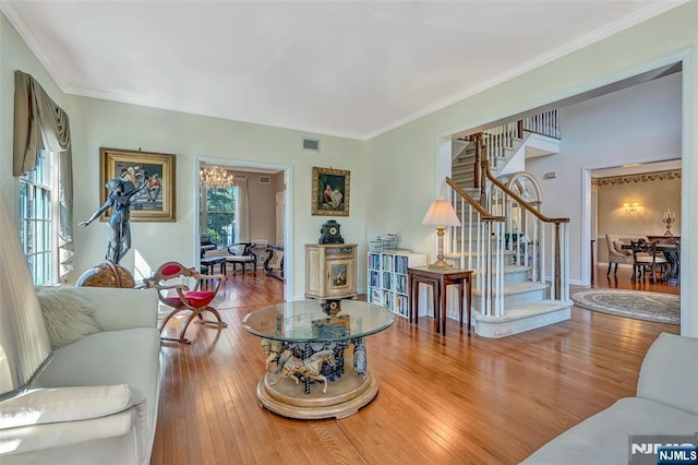  - living room featuring stairway, wood finished floors, crown molding, and a chandelier