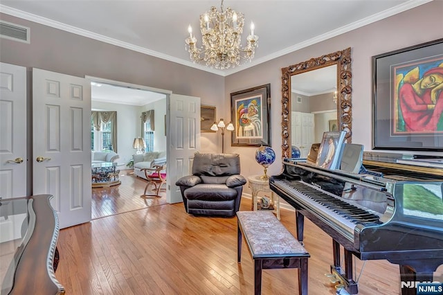  - living area featuring hardwood / wood-style floors, a chandelier, ornamental molding, and baseboards