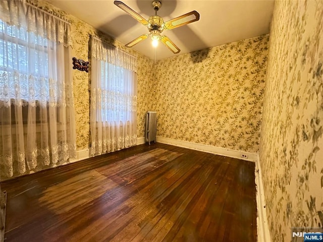 128 Oak Ridge Ave, Nutley, NJ 07110 - empty room featuring dark wood finished floors, radiator heating unit, wallpapered walls, ceiling fan, and baseboards