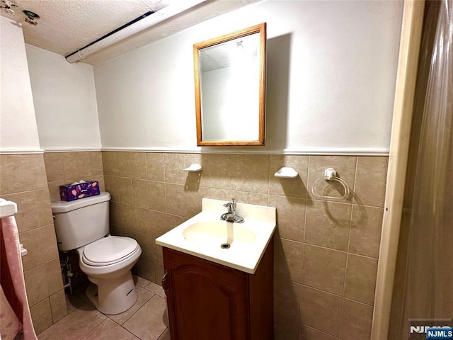 128 Oak Ridge Ave, Nutley, NJ 07110 - half bathroom featuring a wainscoted wall, vanity, toilet, tile walls, and tile patterned floors