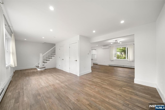 93 Stelfox St, Demarest, NJ 07627 - unfurnished living room featuring a baseboard radiator, an AC wall unit, stairs, wood finished floors, and recessed lighting