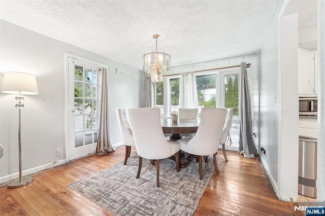 26 Howard Pl, Waldwick, NJ 07463 - dining room featuring a chandelier, wood-type flooring, a textured ceiling, and baseboards