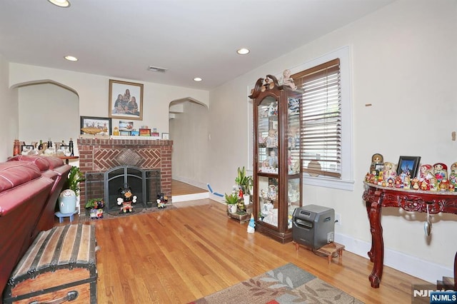 1154 Summit Ave, Teaneck, NJ 07666 - living area featuring arched walkways, wood finished floors, a brick fireplace, baseboards, and recessed lighting