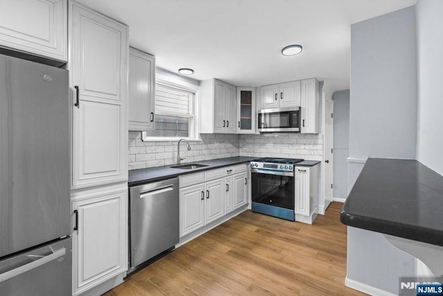 49 Oakwood Ave, Bloomfield, NJ 07003 - kitchen featuring stainless steel appliances, a sink, dark countertops, decorative backsplash, and light wood-type flooring