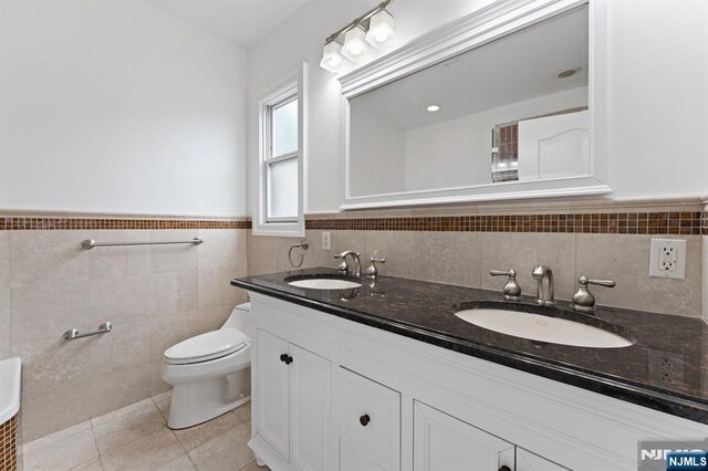 52 Myrtle Ave Unit B, Edgewater, NJ 07020 - bathroom with double vanity, toilet, tile walls, tile patterned flooring, and a wainscoted wall