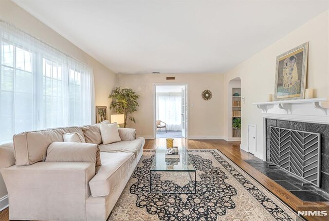 173 Sheridan Ave, Ho-Ho-Kus, NJ 07423 - living area with arched walkways, wood finished floors, a tile fireplace, and baseboards