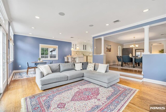 173 Sheridan Ave, Ho-Ho-Kus, NJ 07423 - living room featuring ornate columns, a chandelier, baseboards, light wood finished floors, and ornamental molding