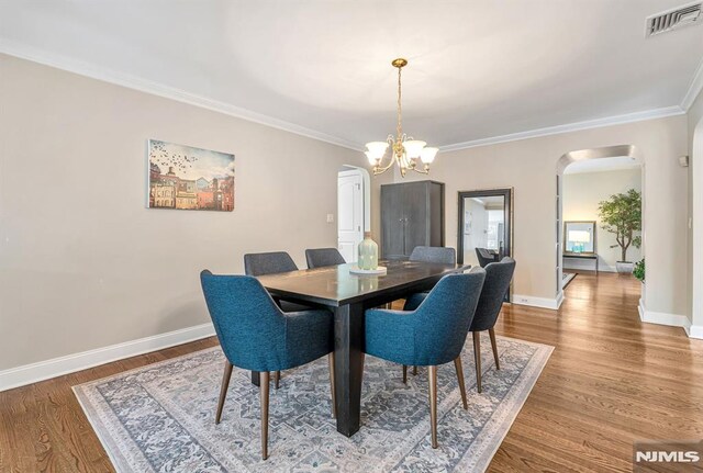 173 Sheridan Ave, Ho-Ho-Kus, NJ 07423 - dining area with arched walkways, a chandelier, ornamental molding, baseboards, and wood finished floors