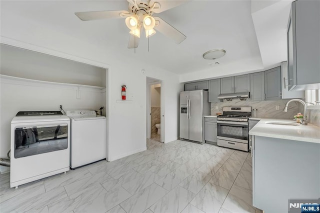 2410 3rd St, Fort Lee, NJ 07024 - kitchen with appliances with stainless steel finishes, gray cabinetry, under cabinet range hood, light countertops, and washing machine and clothes dryer