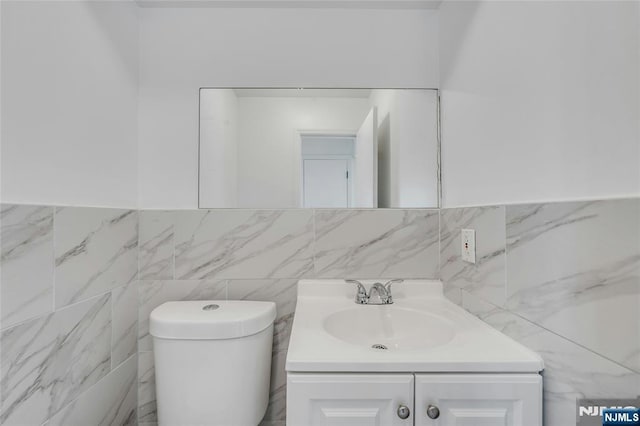 2410 3rd St, Fort Lee, NJ 07024 - half bath featuring vanity, toilet, tile walls, and wainscoting