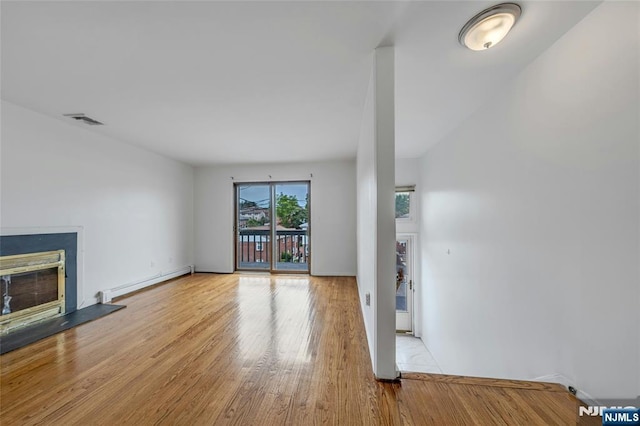 2410 3rd St, Fort Lee, NJ 07024 - unfurnished living room featuring baseboard heating, wood finished floors, a glass covered fireplace, and baseboards