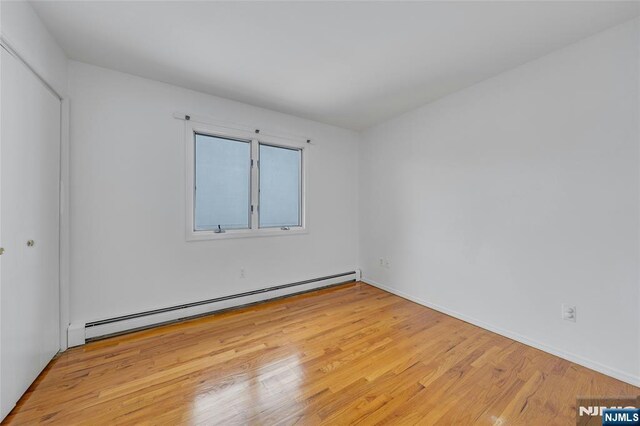 2410 3rd St, Fort Lee, NJ 07024 - spare room featuring a baseboard heating unit, wood finished floors, and baseboards