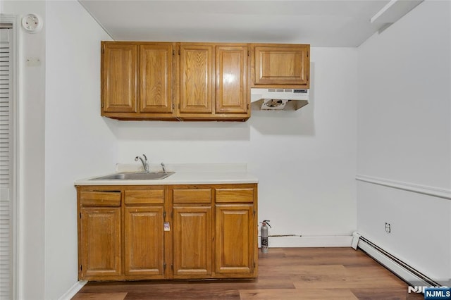 2410 3rd St, Fort Lee, NJ 07024 - kitchen featuring a sink, a baseboard radiator, under cabinet range hood, dark wood-type flooring, and light countertops