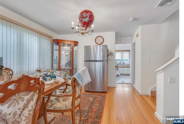 2410 3rd St, Fort Lee, NJ 07024 - dining area with light wood-style flooring, a chandelier, and baseboards