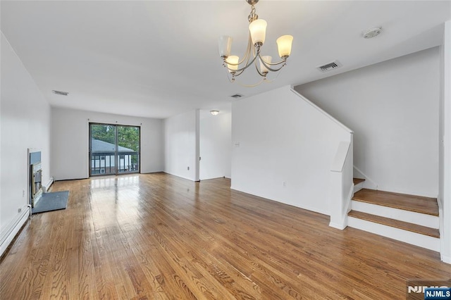 2410 3rd St, Fort Lee, NJ 07024 - unfurnished living room featuring a chandelier, a baseboard radiator, stairs, and light wood-type flooring