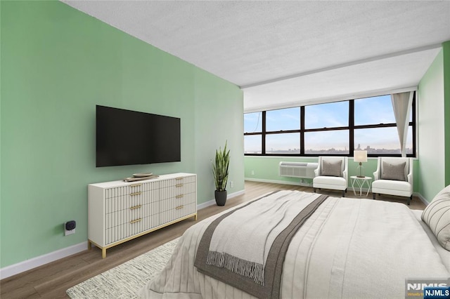 7004 E Kennedy Blvd Unit 28C, Guttenberg, NJ 07093 - bedroom with baseboards, wood finished floors, a wall mounted AC, and a textured ceiling