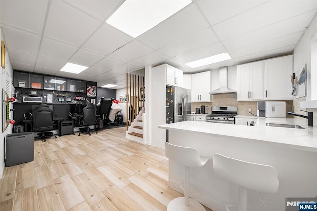 344 Northwood Way, Palisades Park, NJ 07650 - kitchen featuring wall chimney exhaust hood, stainless steel appliances, a sink, a drop ceiling, and light wood-type flooring