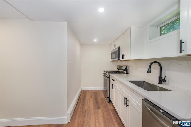 112 Fern St, Twp Of Washington, NJ 07676 - kitchen with stainless steel appliances, a sink, white cabinets, light wood finished floors, and light countertops
