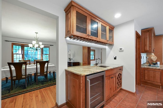 68 Birch St, Ramsey, NJ 07446 - kitchen featuring beverage cooler, brown cabinetry, a sink, a chandelier, and light stone countertops