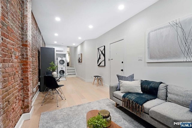 606 1st St Unit 1, Hoboken, NJ 07030 - living area featuring stacked washer / drying machine, brick wall, light wood-style flooring, recessed lighting, and baseboards