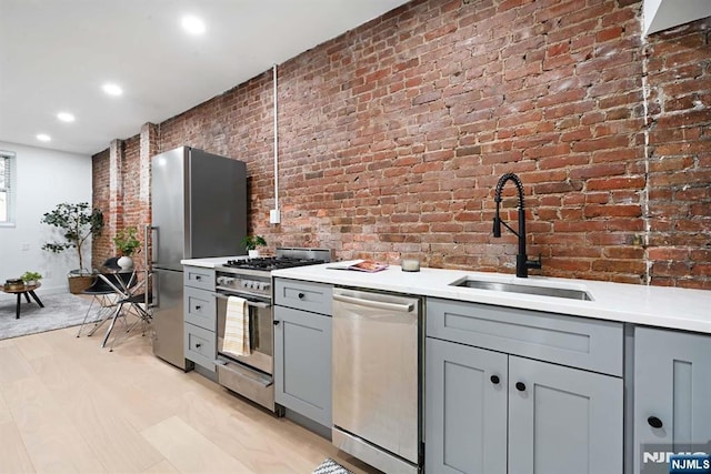 606 1st St Unit 1, Hoboken, NJ 07030 - kitchen featuring stainless steel appliances, gray cabinetry, brick wall, a sink, and light countertops