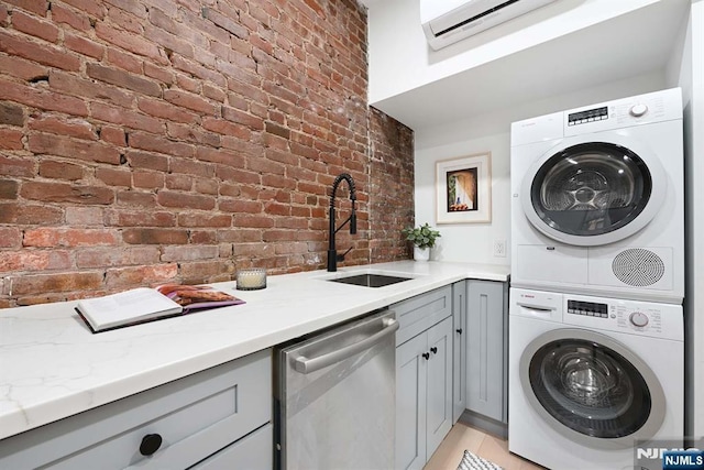 606 1st St Unit 1, Hoboken, NJ 07030 - laundry room with stacked washer and clothes dryer, brick wall, a sink, a wall mounted air conditioner, and light tile patterned floors