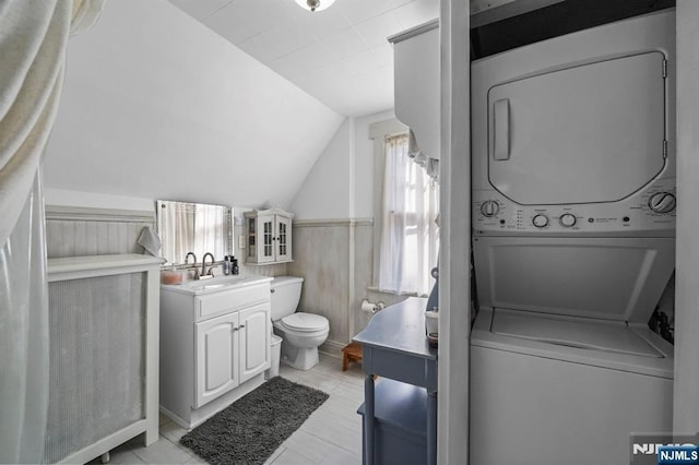 11 Harrington St, Hillsdale, NJ 07642 - bathroom featuring estacked washer and dryer, vanity, lofted ceiling, toilet, and wainscoting