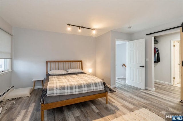62 Valley Rd, Glen Rock, NJ 07452 - bedroom with a barn door, light wood-type flooring, track lighting, baseboard heating, and baseboards