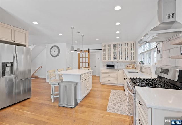 322 E Midland Ave, Paramus, NJ 07652 - kitchen featuring appliances with stainless steel finishes, a sink, a barn door, wall chimney range hood, and light wood finished floors